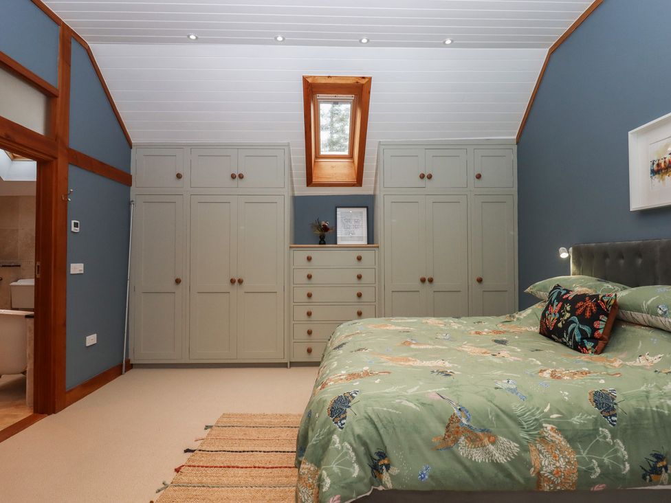 A bedroom with a bed and closets at Pylemoor Cottage in Washfield near Tiverton