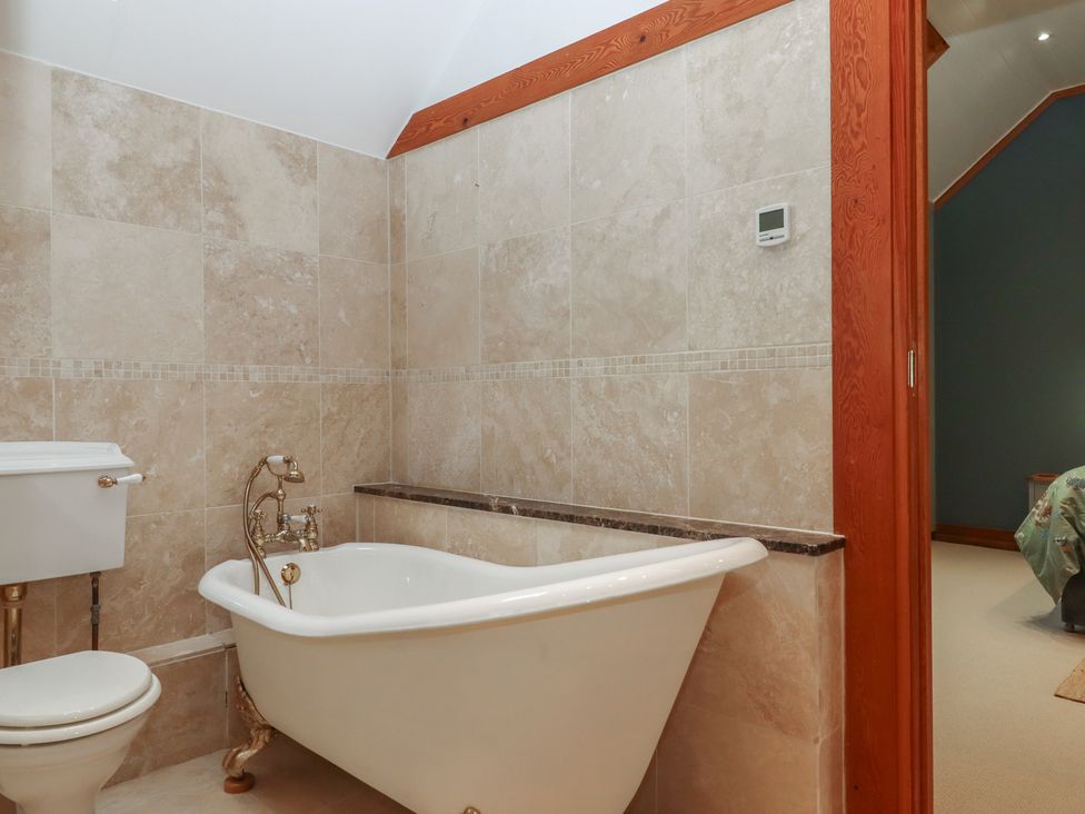 A bathroom with a bathtub and toilet at Pylemoor Cottage in Washfield near Tiverton