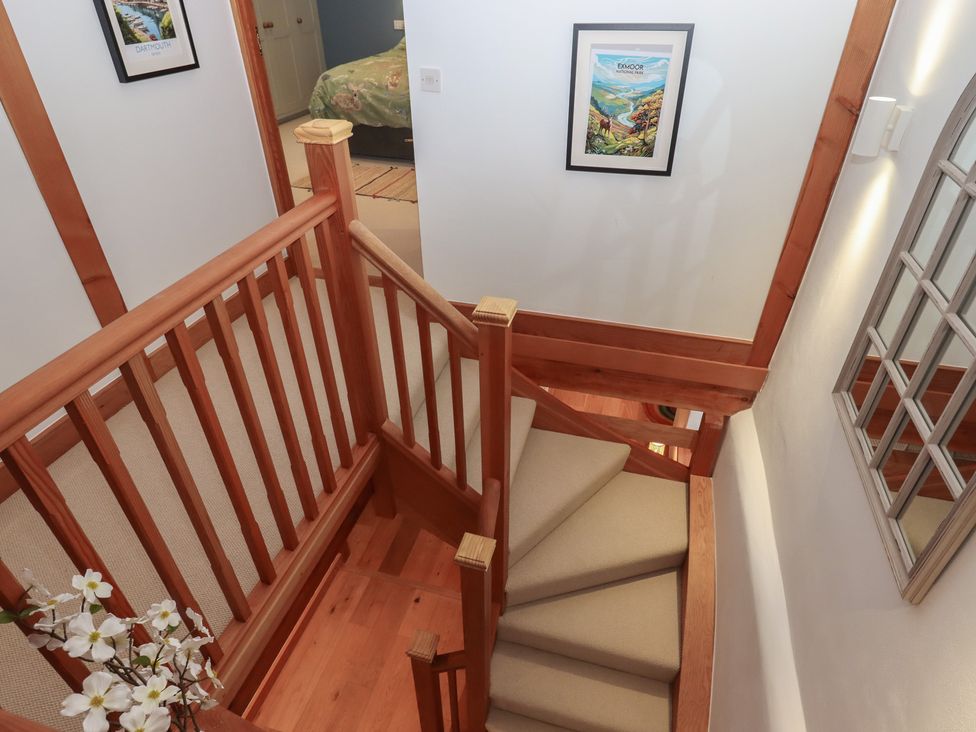 A staircase with wooden handrail in a hallway at Pylemoor Cottage in Washfield near Tiverton
