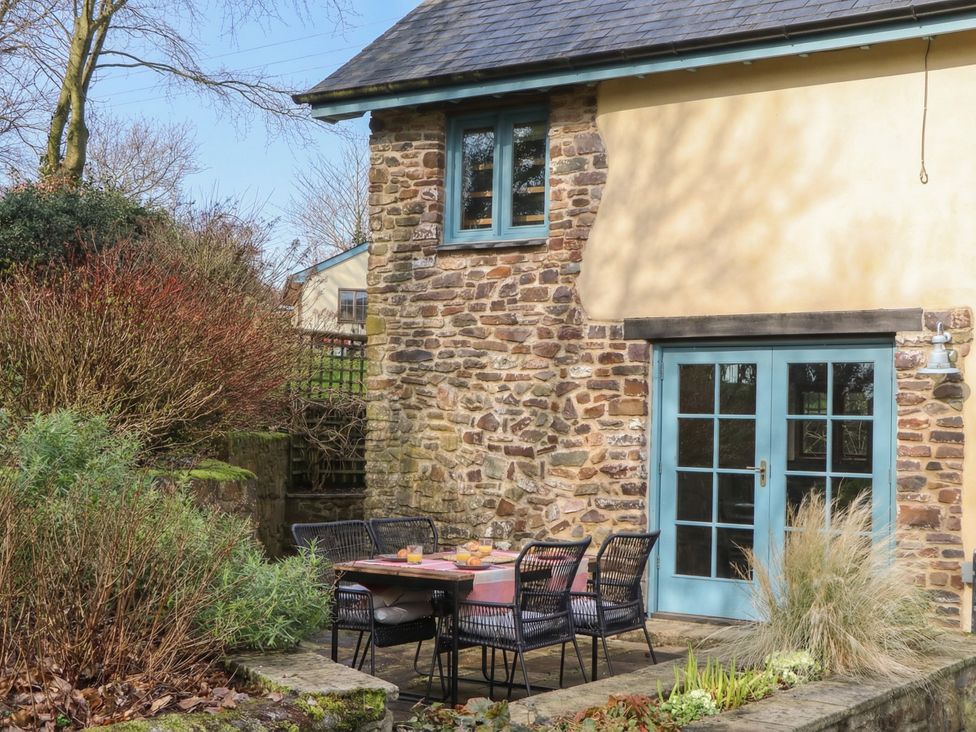 An outdoor seating area with a table and chairs at Pylemoor Cottage in Washfield near Tiverton