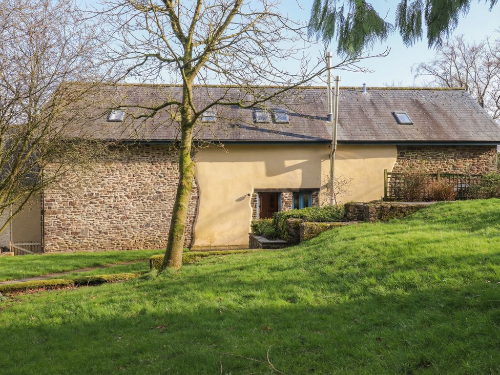 A building with windows and door surrounded by grass and trees at Pylemoor Cottage Washfield near Tiverton