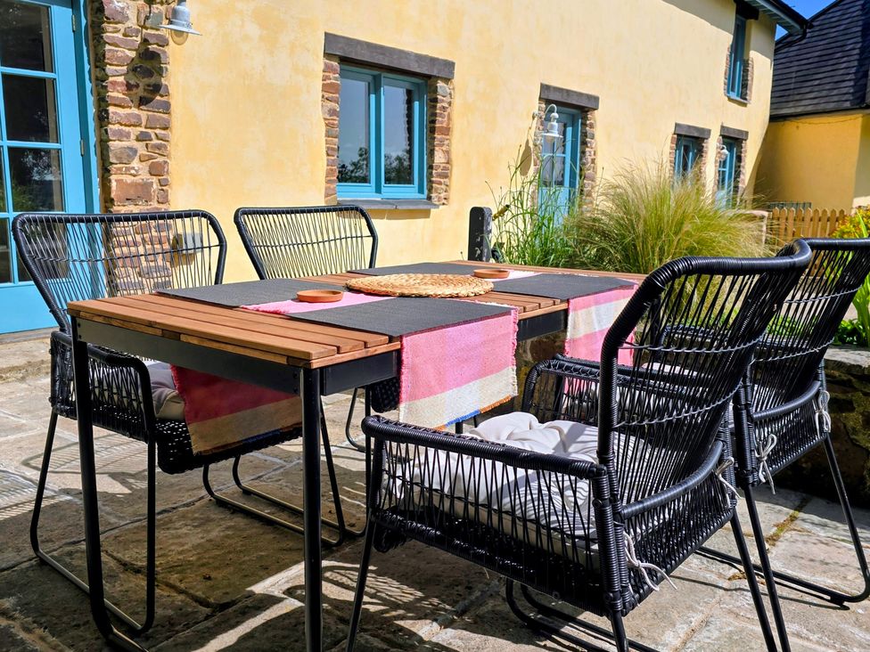An outdoor dining area with chairs and a table at Pylemoor Cottage in Washfield near Tiverton