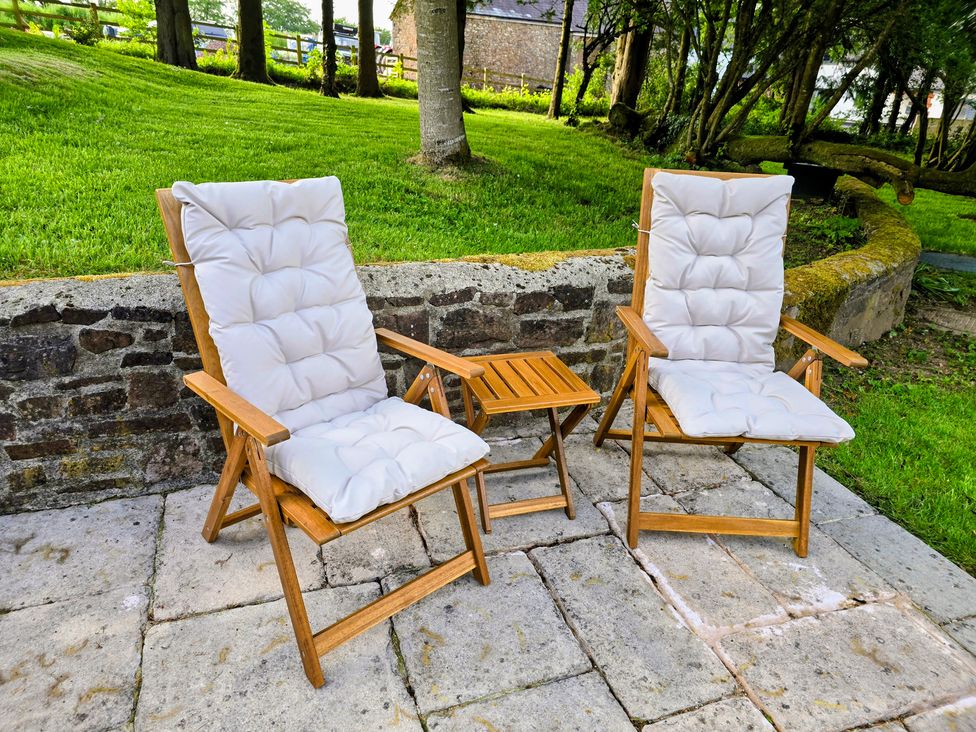 A patio with two reclining chairs and a small table at Pylemoor Cottage Washfield near Tiverton