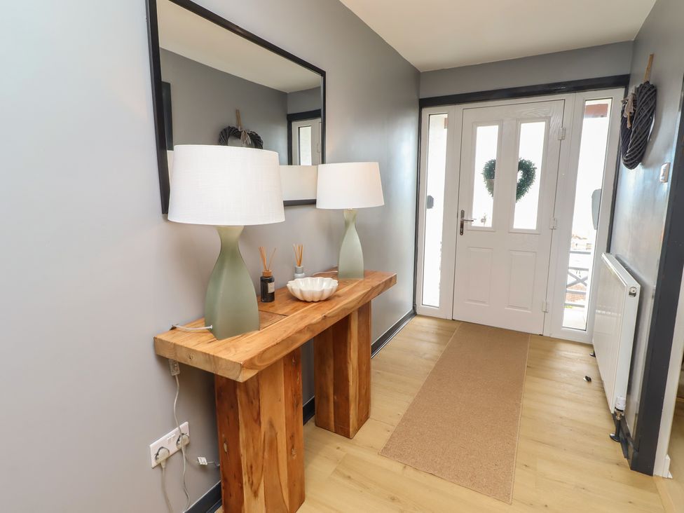 A hallway with a console table, lamps, and a mirror at Tigh-Na-Mara Retreat