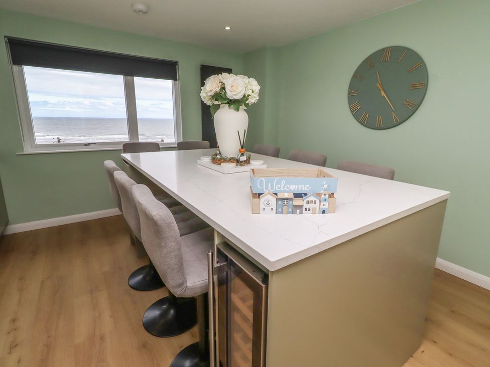 A kitchen with a table and chairs overlooking the sea at Tigh-Na-Mara Retreat