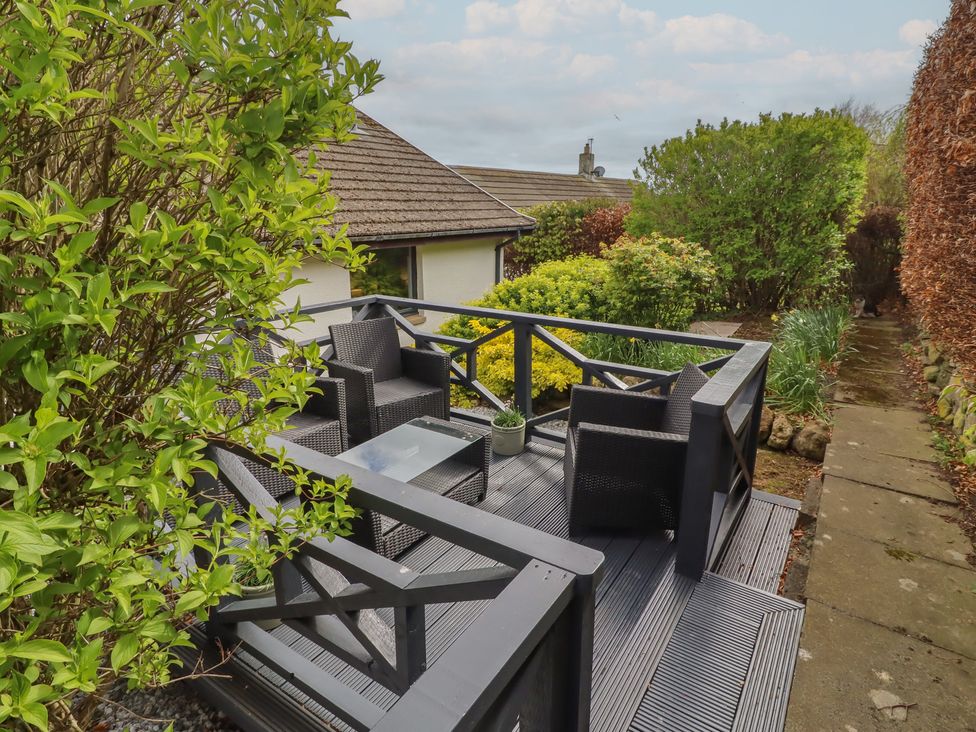 A deck with chairs and a table surrounded by greenery at Tigh-Na-Mara Retreat