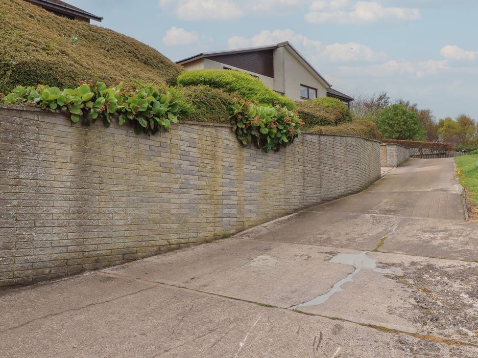 A driveway with a brick wall and hedges at Tigh-Na-Mara Retreat