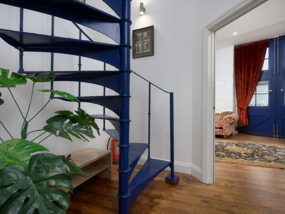 A spiral staircase with a plant and door leading to living room at The Mayflower in Plymouth