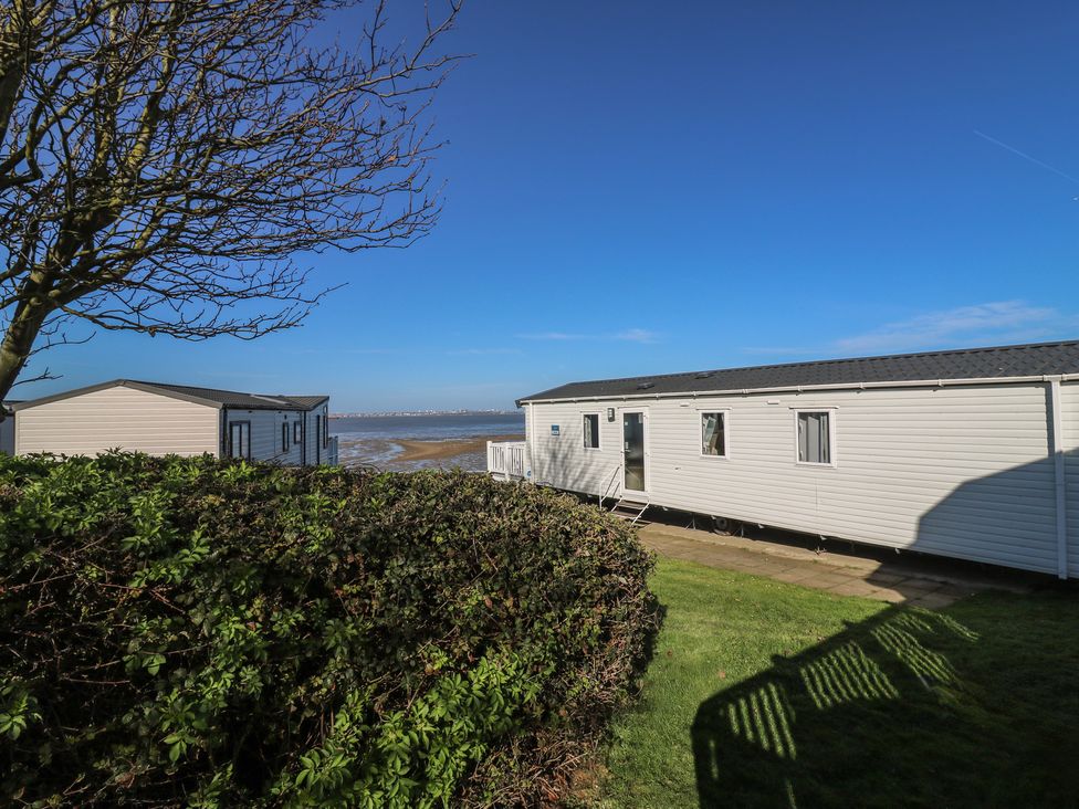 A caravan with a pathway and bushes at Ocean Breeze Escape in Allhallows