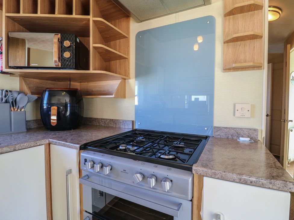 A kitchen with a gas stove and microwave at Ocean Breeze Escape in Allhallows
