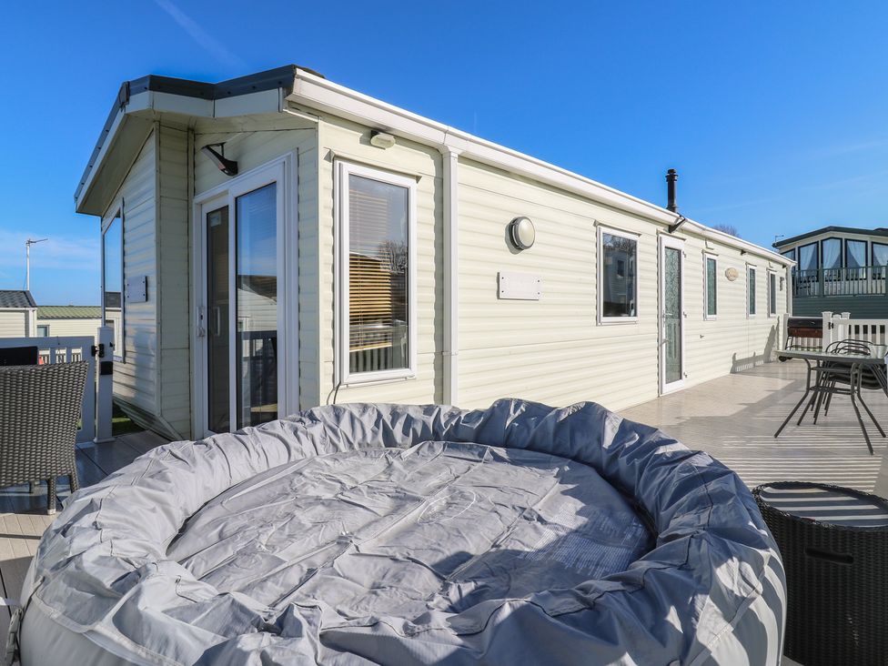 An outdoor area with a hot tub and seating at Ocean Breeze Escape in Allhallows