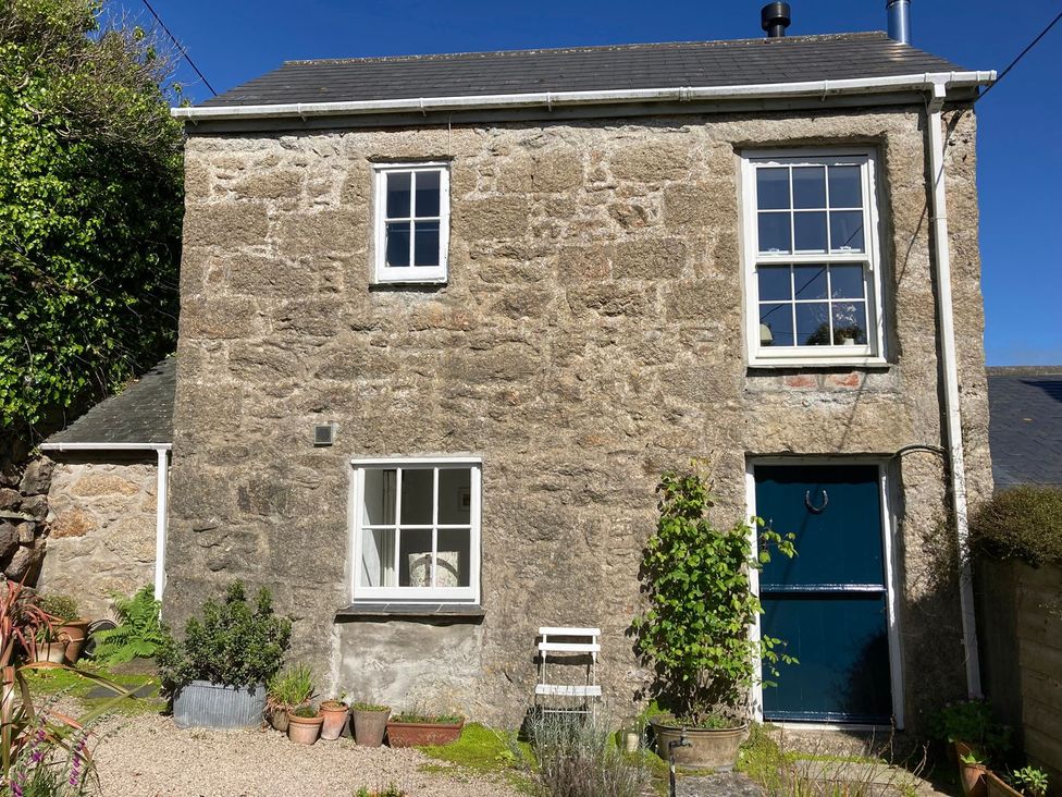 A stone house with a blue door and plants outside at The Old Studio in Penzance