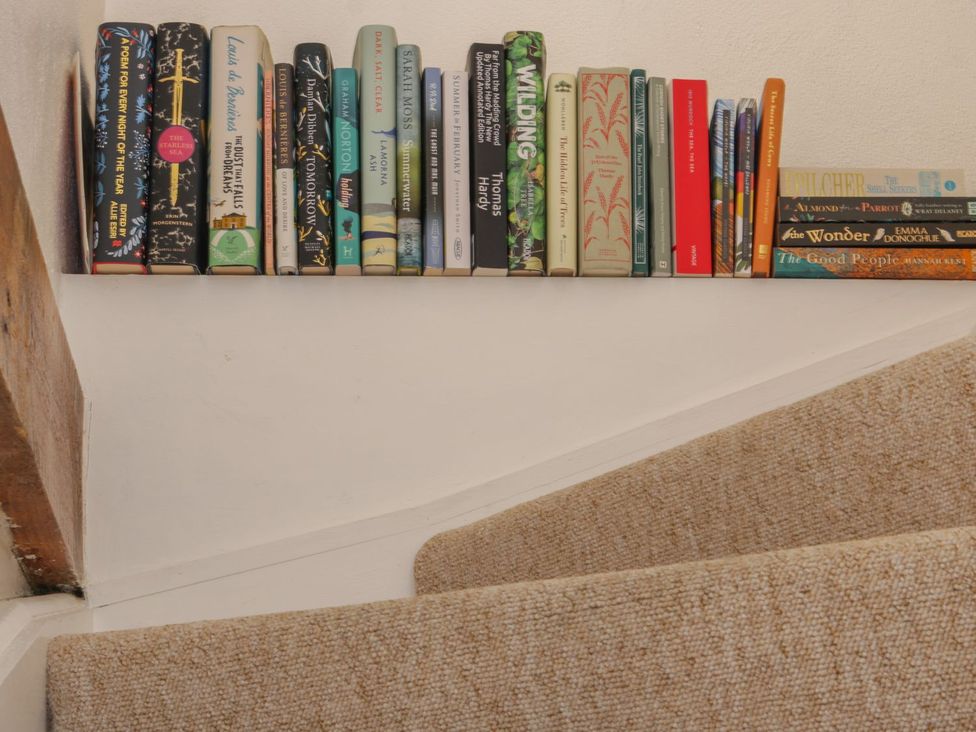 A staircase with a shelf of books at The Old Studio in Penzance