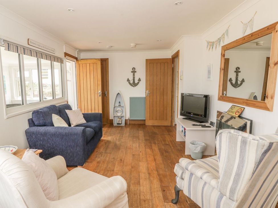 A living room with a sofa, armchair, and television at Wagtail Cottage