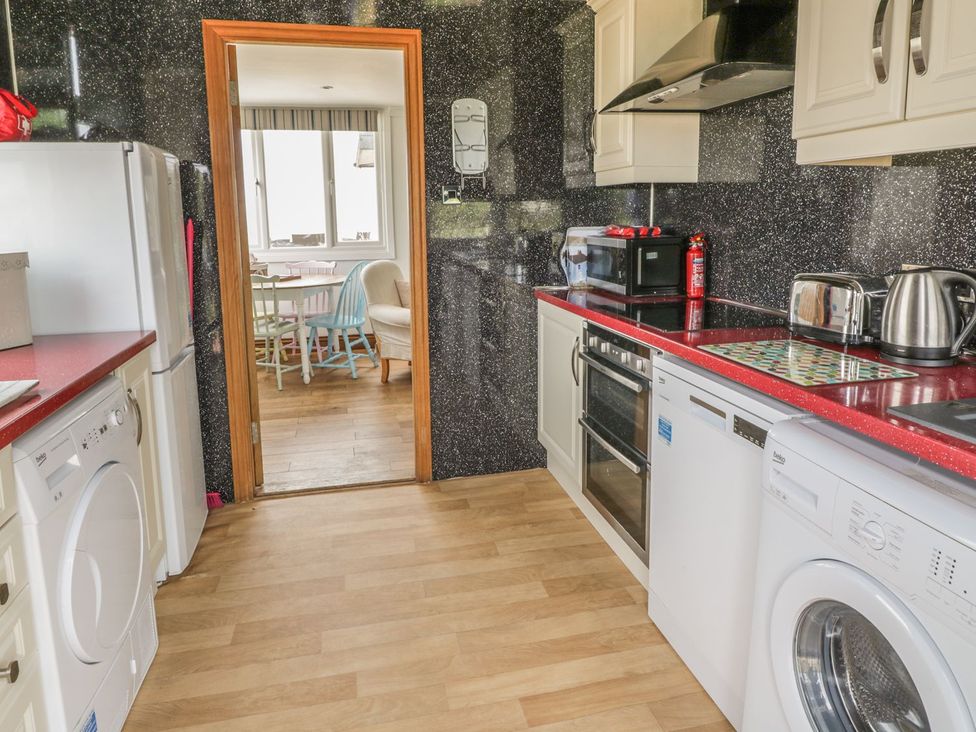 A kitchen with appliances and a door leading to a dining area at Wagtail Cottage 