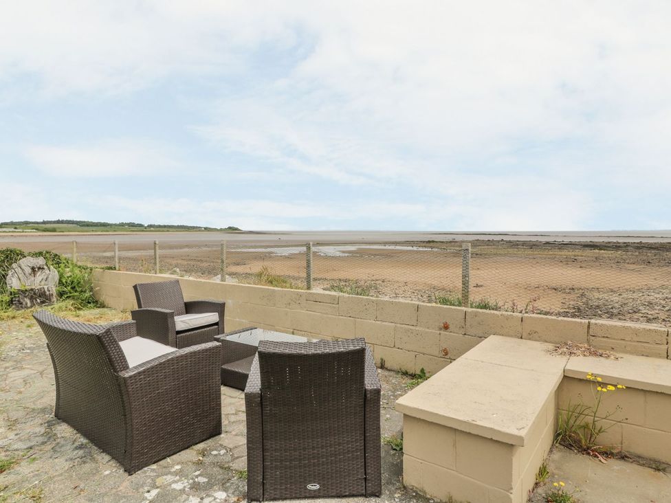An outdoor seating area with chairs and table overlooking the beach at Wagtail Cottage