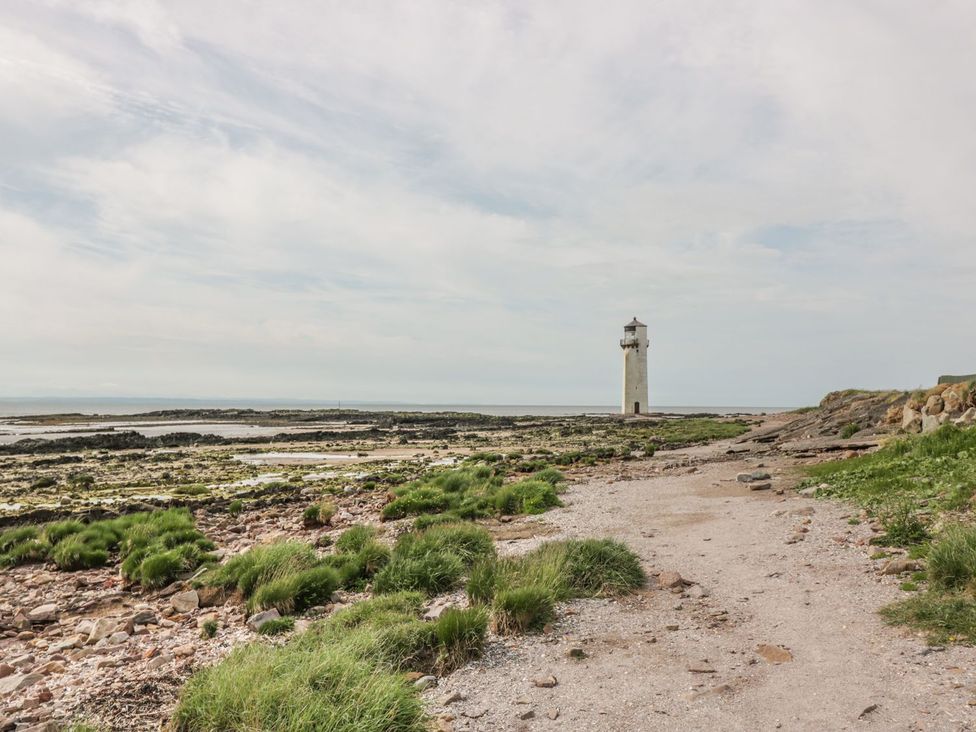 A coastal scene with a lighthouse and rocky shore at Wagtail Cottage