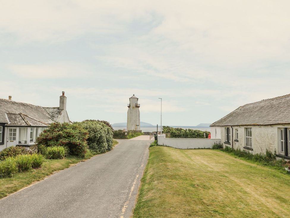 A lighthouse with houses along the road at Wagtail Cottage