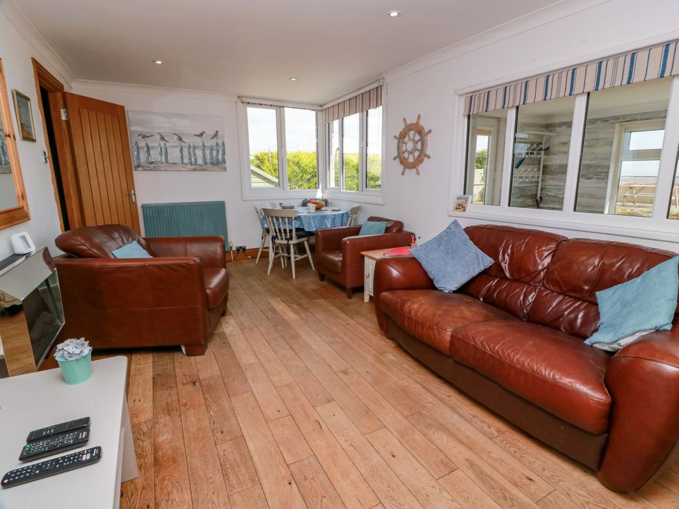 A living room with sofas and a dining table at Wagtail Cottage in Southerness
