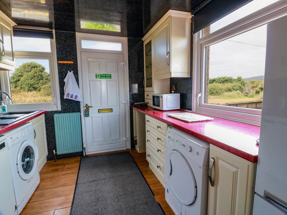 A kitchen with appliances and a door to the outside at Wagtail Cottage Southerness