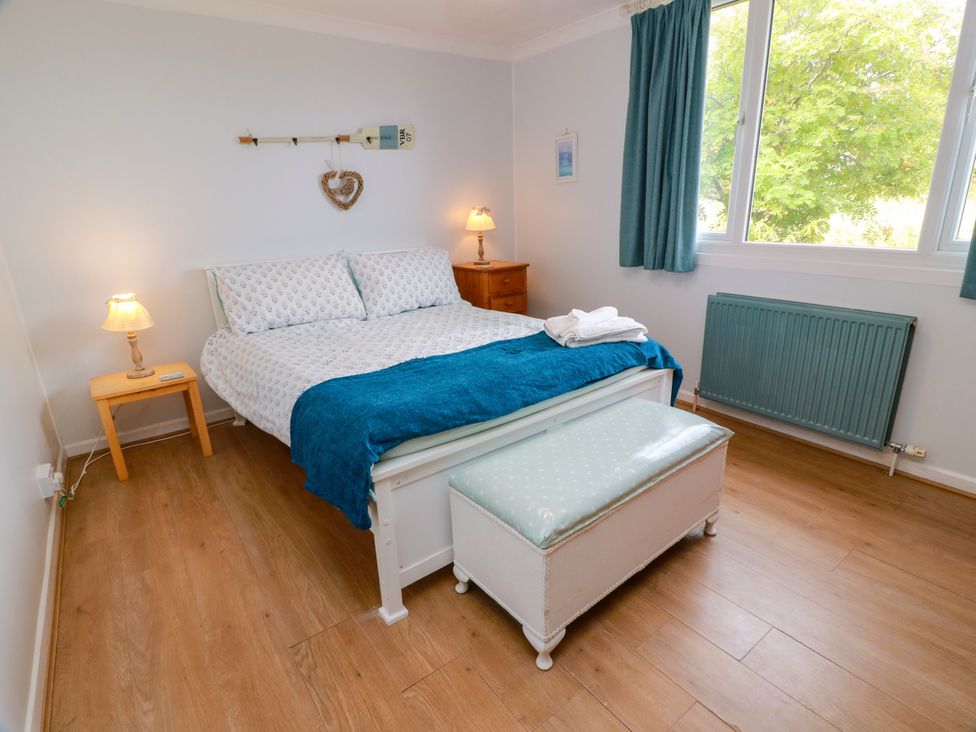 A bedroom with a bed and bedside table at Wagtail Cottage in Southerness