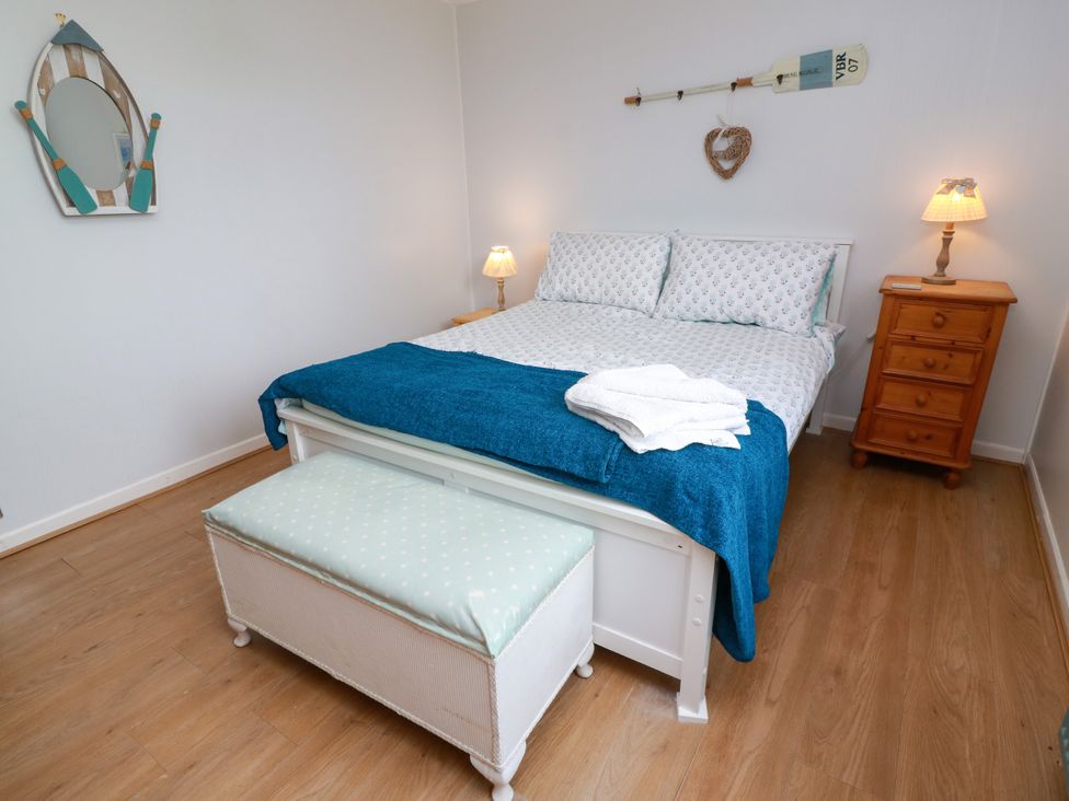 A bedroom with a bed and nightstand at Wagtail Cottage in Southerness