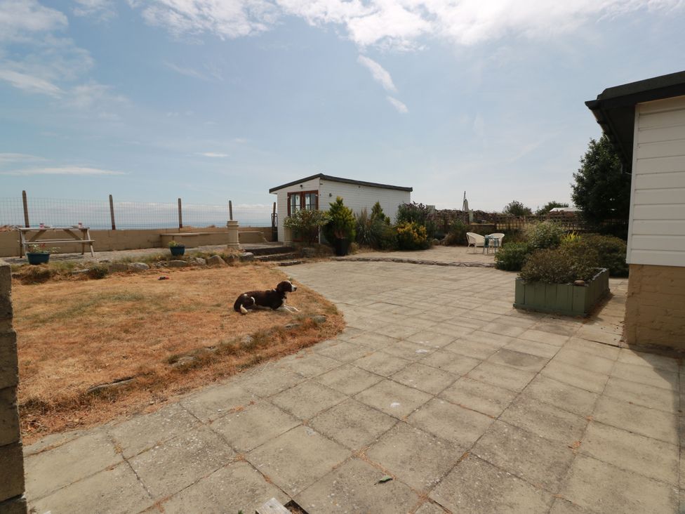 A garden area with a dog lying on the ground at Wagtail Cottage in Southerness