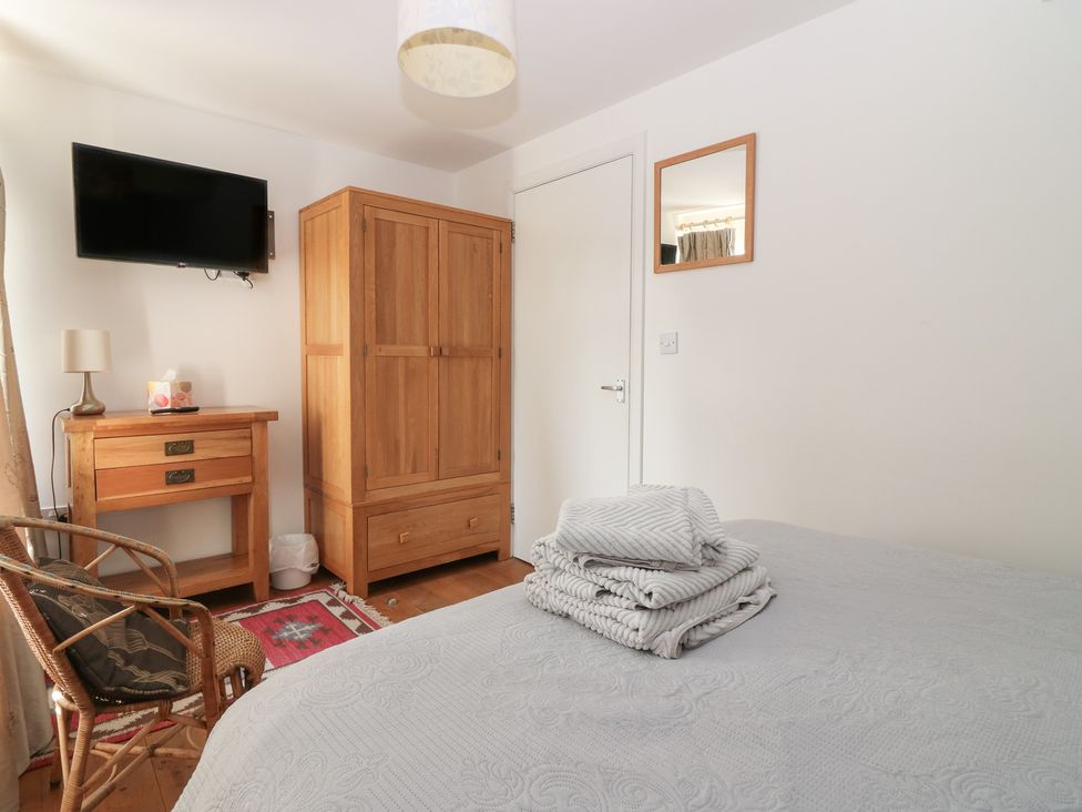 A bedroom with a bed, television, and wooden wardrobe at Mill Wharf in Berwick-upon-Tweed