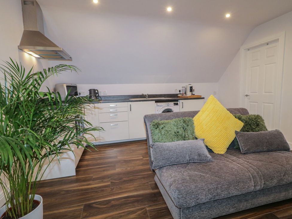A living room with a sofa and kitchen counter at The Loft - 96B