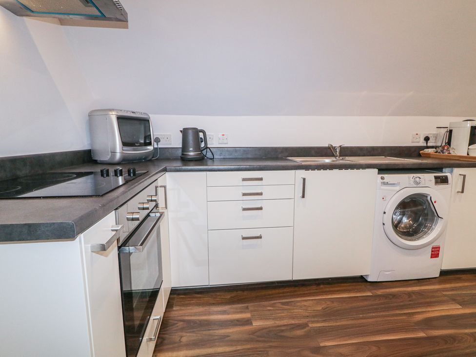 A kitchen with appliances including a washing machine and microwave at The Loft - 96B