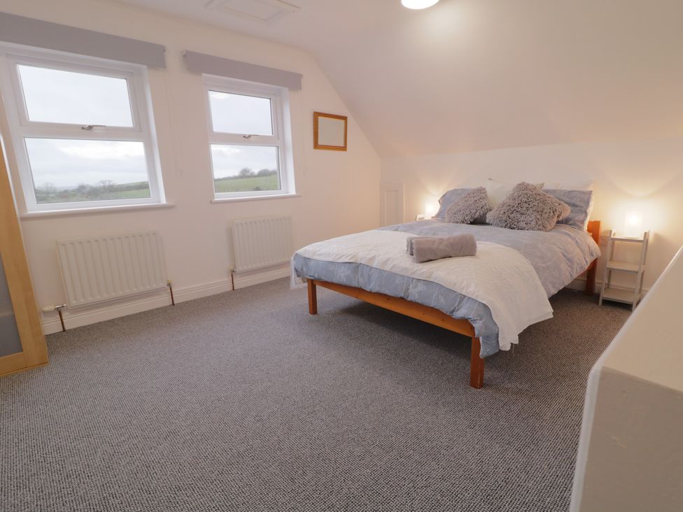 A bedroom with a bed and windows at The Loft - 96B