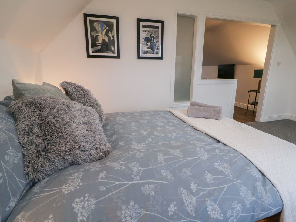 A bedroom with a bed and wall art at The Loft - 96B 