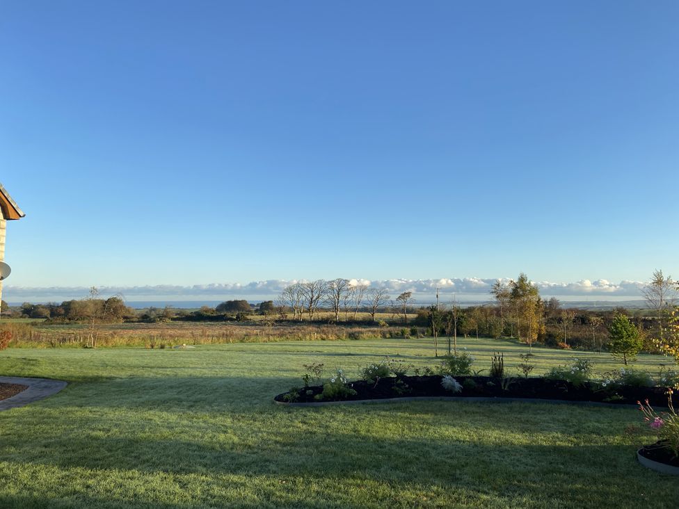 A view of grass and trees with ocean in the background at The Loft - 96B