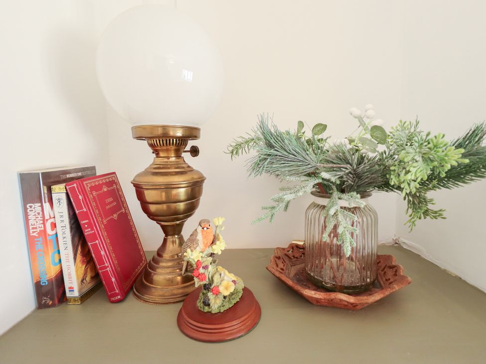 A table with a lamp, books, a figurine, and a plant at 3 Rectory Row