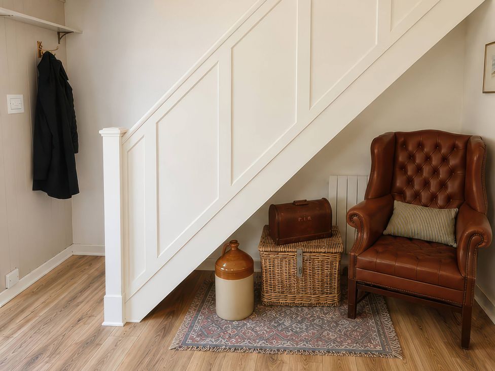 An entryway featuring a staircase and a brown armchair at The Monks Retreat Great Massingham