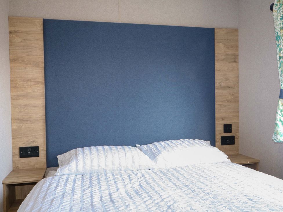 A bed with a blue headboard and bedside tables at 0028 South Beach