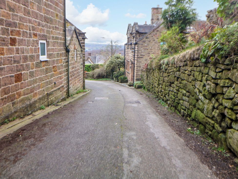 A street with stone houses and a paved road at Nature’s Retreat in Matlock