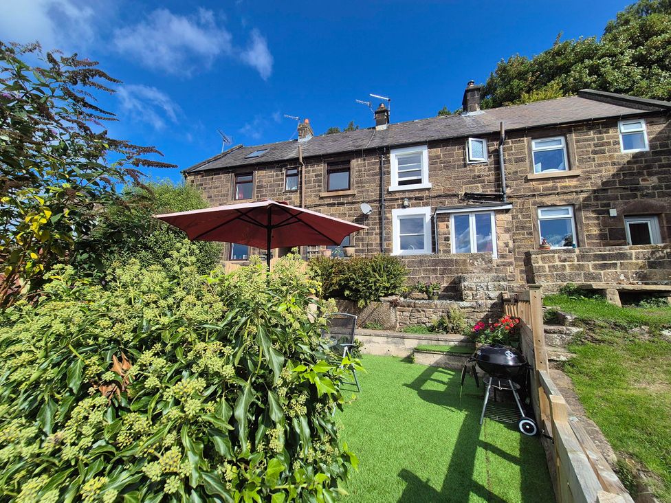 A garden with a house and BBQ grill at Nature’s Retreat in Holloway