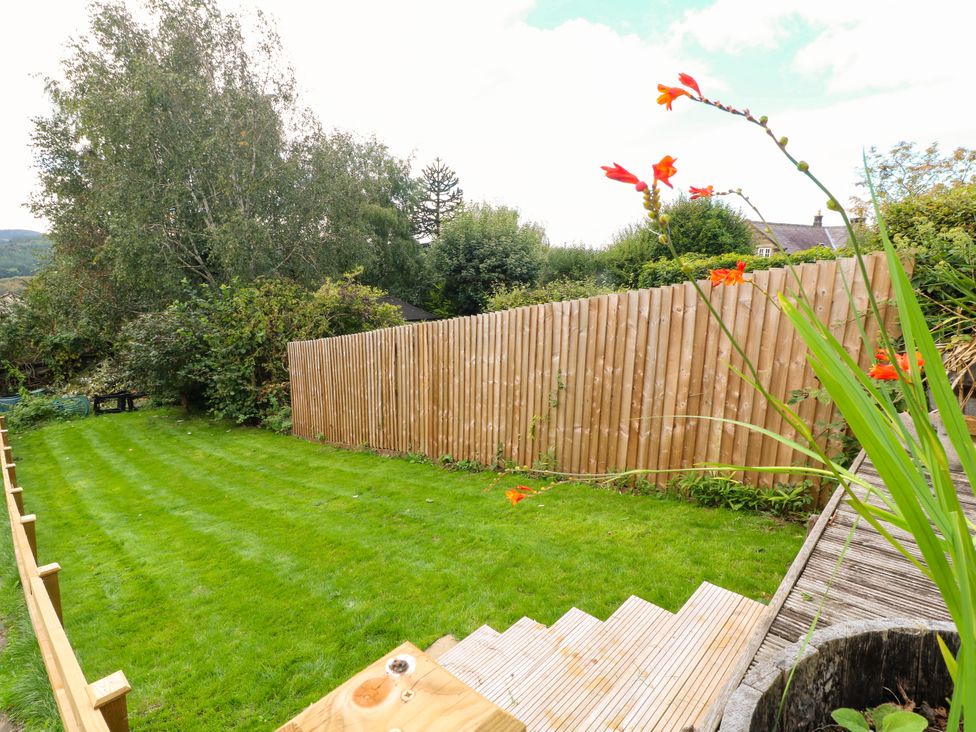 A garden with grass, steps, trees, and a wooden fence at Nature’s Retreat in Holloway