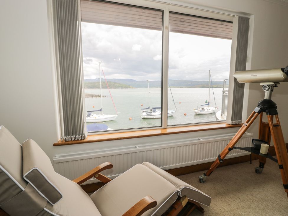A living room with a view of boats and a telescope at The Boat Yard Apartment Porthmadog
