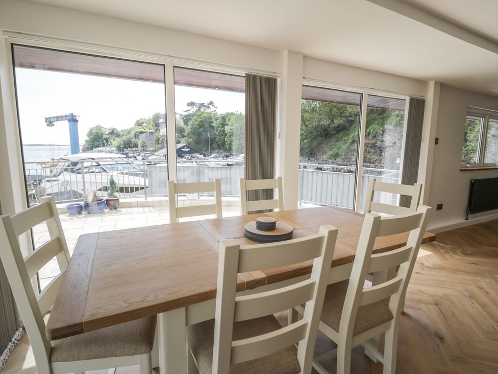 A dining room with a table and chairs overlooking boats at The Boat Yard Apartment in Porthmadog