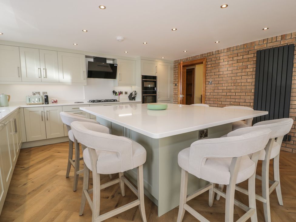 A kitchen with cabinets, stove, oven, sink, and bar stools at The Boat Yard Apartment in Porthmadog