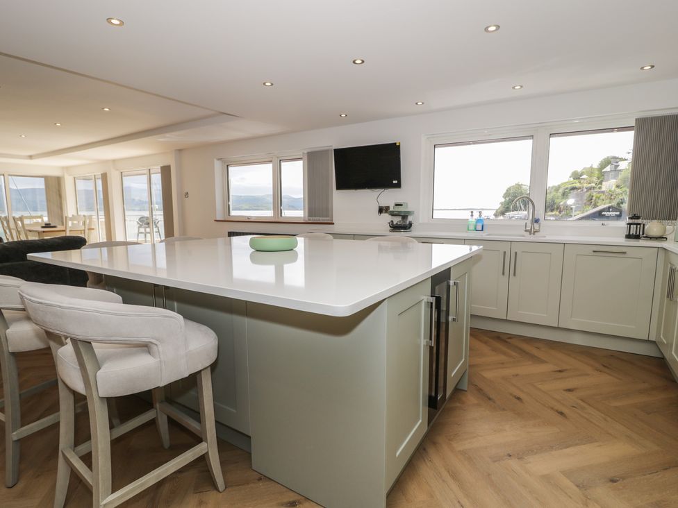 A kitchen with an island and bar stools at The Boat Yard Apartment Porthmadog