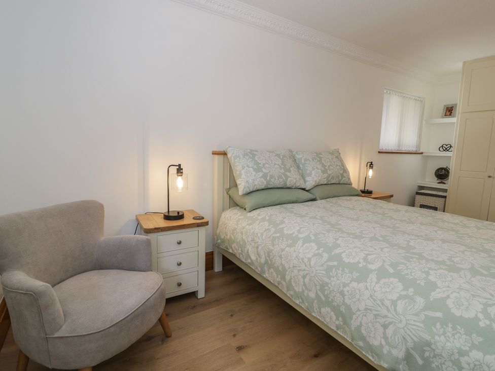 A bedroom with a bed and a chair at The Boat Yard Apartment in Porthmadog
