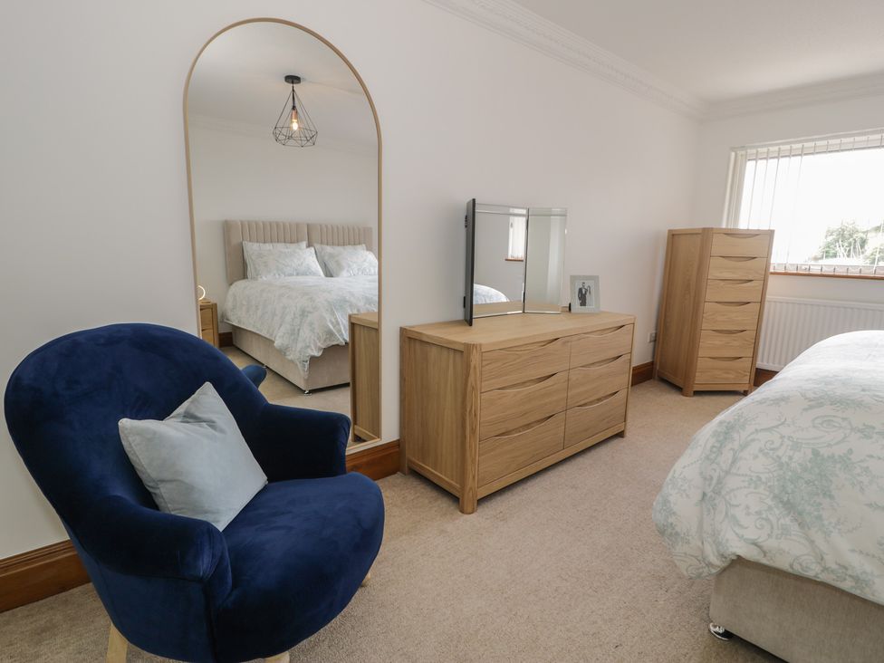 A bedroom with a bed, dressing table, and chair at The Boat Yard Apartment Porthmadog