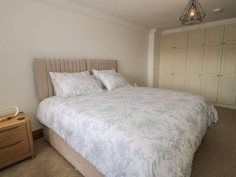 A bedroom with a bed and wardrobe at The Boat Yard Apartment Porthmadog