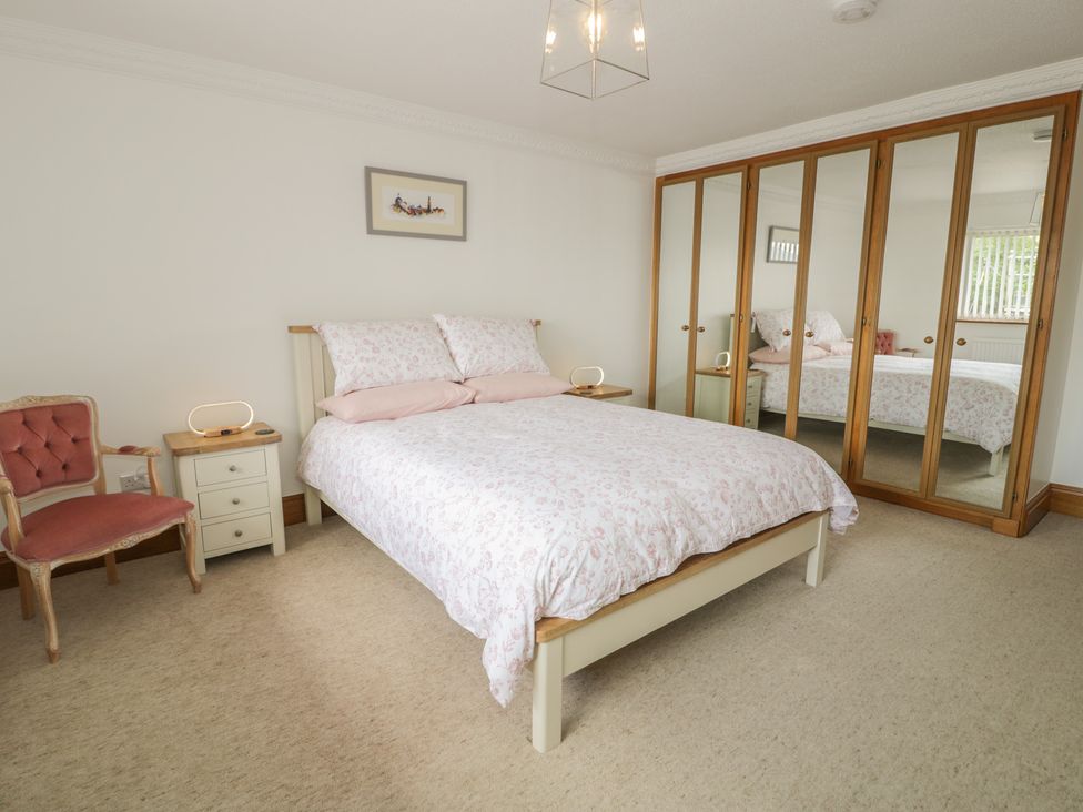 A bedroom with a bed and mirrored wardrobe at The Boat Yard Apartment Porthmadog