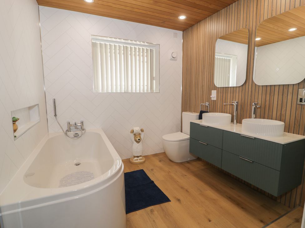 A bathroom with a bathtub and double sinks at The Boat Yard Apartment in Porthmadog