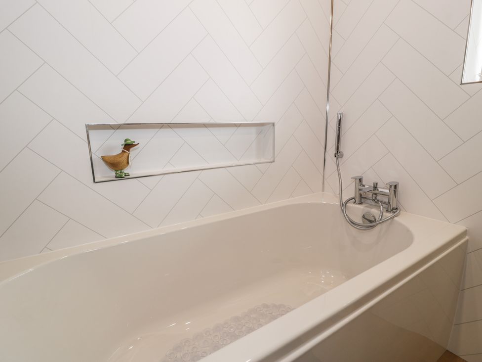 A bathroom with a bathtub and wall-mounted faucet at The Boat Yard Apartment in Porthmadog