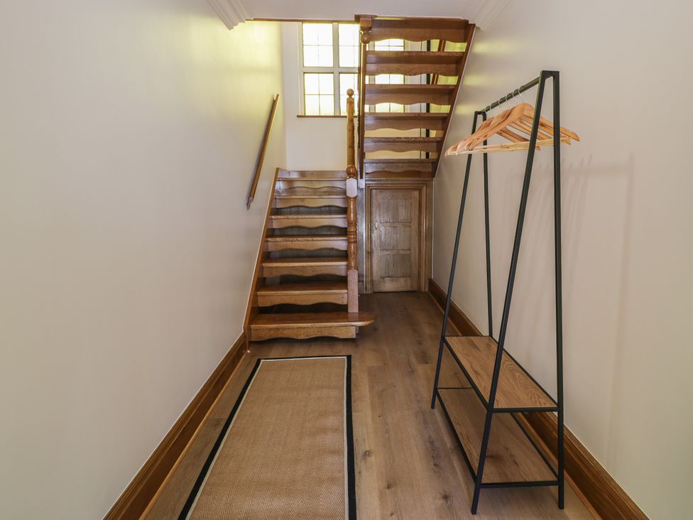 A hallway with a staircase and a hanging coat rack at The Boat Yard Apartment Porthmadog